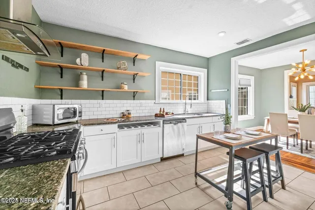 a kitchen with stainless steel appliances a stove a sink and white cabinets