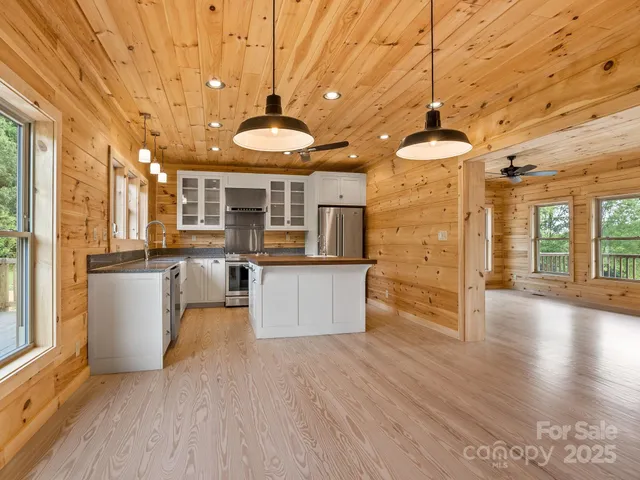 a view of a living room and kitchen with furniture wooden floor and windows