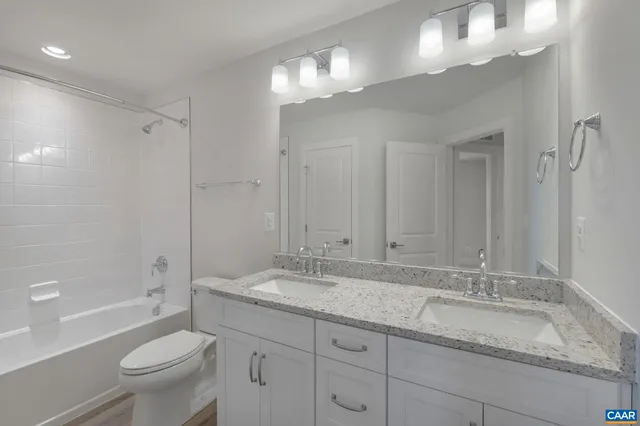 a bathroom with a granite countertop sink a toilet and a large mirror