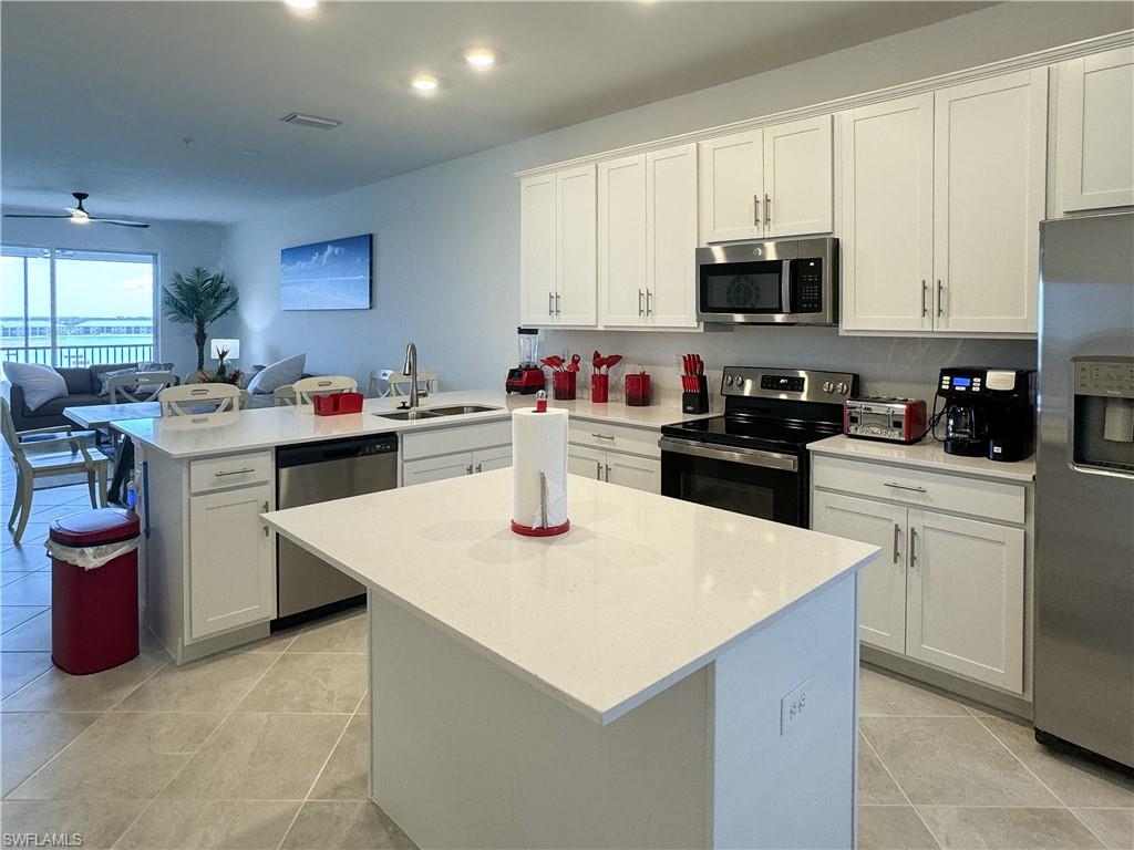 a kitchen with stainless steel appliances a white stove top oven a sink a refrigerator and white cabinets