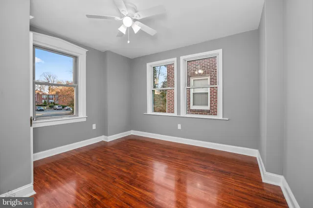 a view of empty room with wooden floor and fan