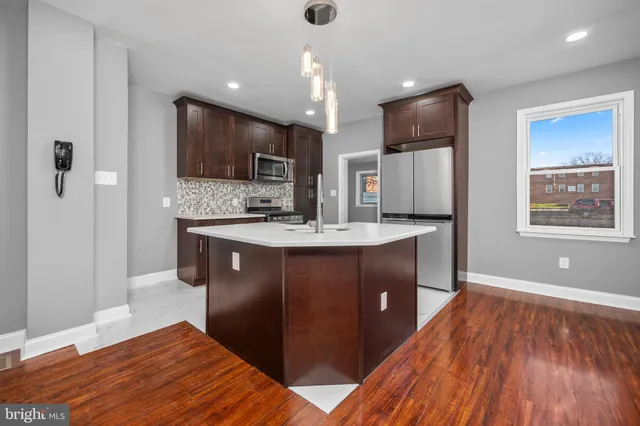 a kitchen with kitchen island granite countertop wooden floors and a sink