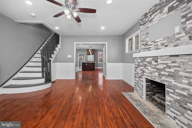 an empty room with wooden floor fireplace and windows