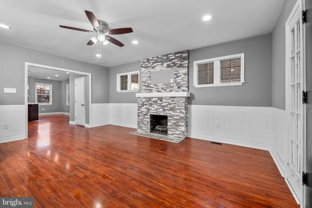 a view of a livingroom with a fireplace a ceiling fan and windows