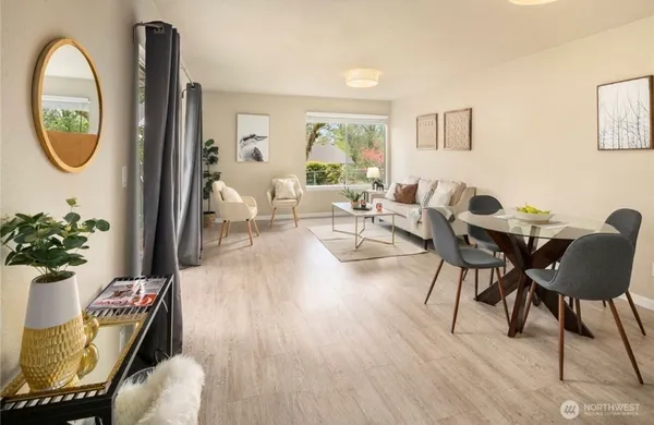 a living room with furniture a mirror a potted plant and a wooden floor