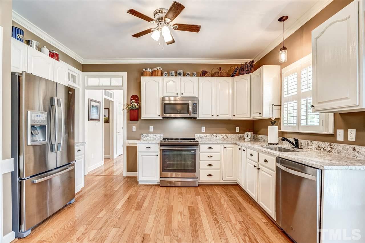 1004 Tyler Farms Drive Raleigh, NC 27603 - Photo 13 of 29 a kitchen with stainless steel appliances granite countertop a stove a refrigerator a sink and white cabinets with wooden floor