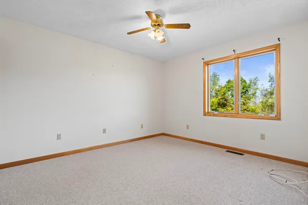 an empty room with windows and fan