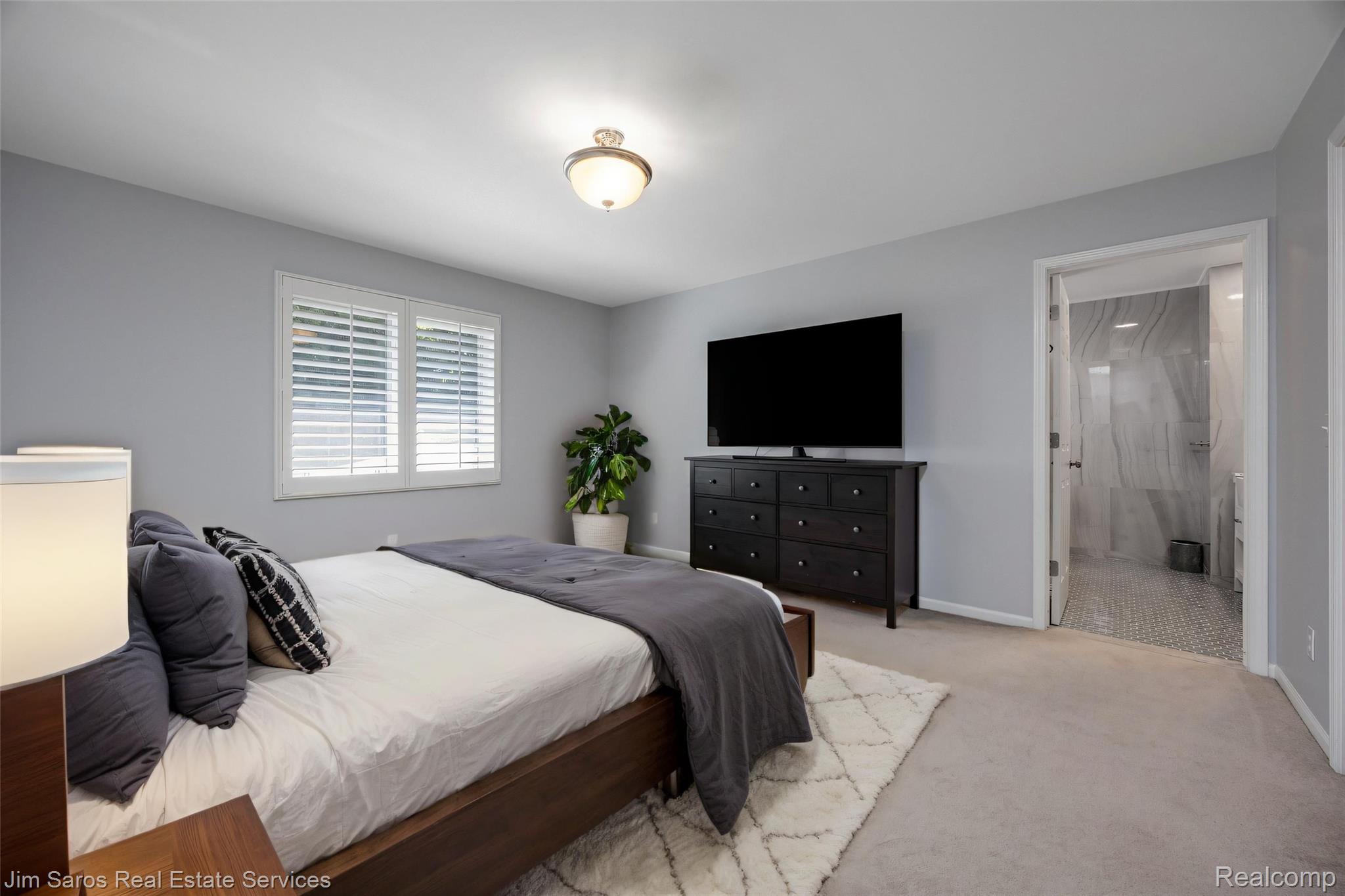 910 Edgemont Park Grosse Pointe, MI 48230 - Photo 31 of 56 Carpeted bedroom featuring a window with white plantation shutters, a ceiling-mounted light fixture, and an open doorway revealing a tiled bathroom