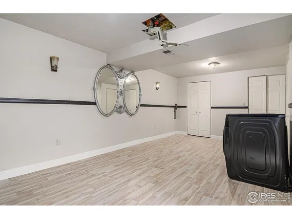 a view of an empty room and a kitchen with wooden floor