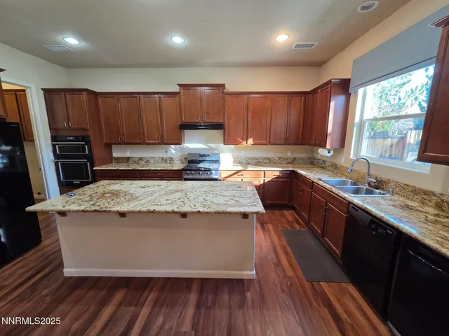 a kitchen with stainless steel appliances granite countertop wooden cabinets a refrigerator and a sink