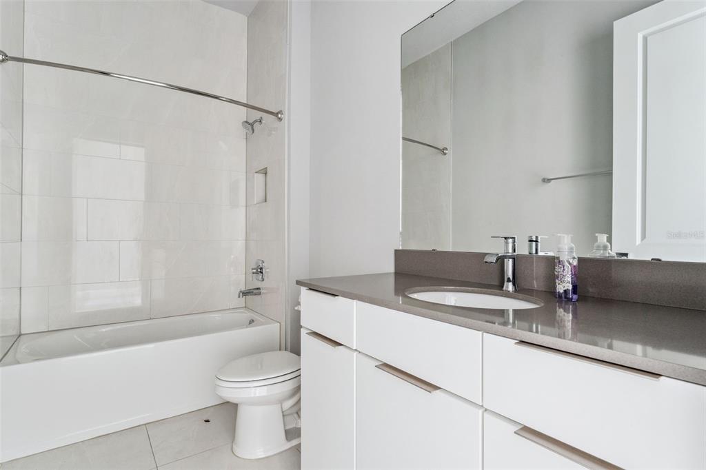 7760 Sandy Ridge Drive, Unit 112 Reunion, FL 34747 - Photo 20 of 23 a bathroom with a granite countertop sink a toilet and shower