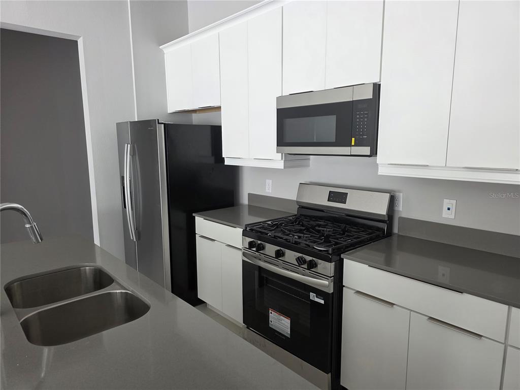7760 Sandy Ridge Drive, Unit 112 Reunion, FL 34747 - Photo 3 of 23 a kitchen with stainless steel appliances granite countertop a refrigerator stove and microwave