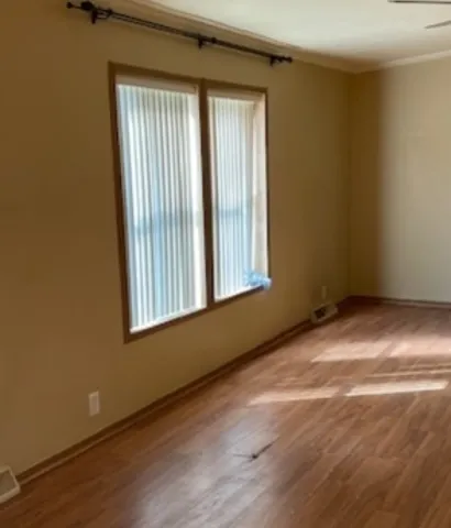 an empty room with wooden floor and windows
