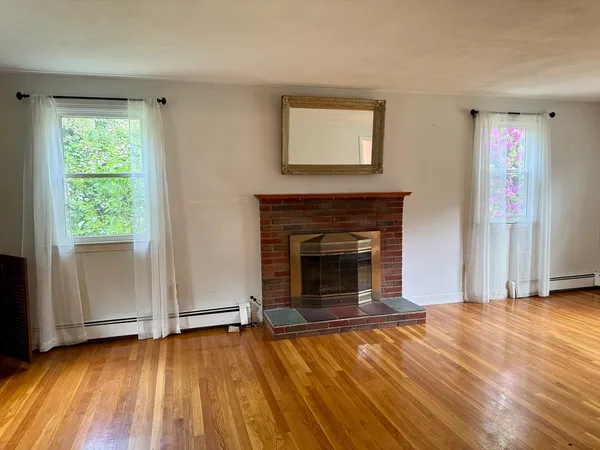 a view of empty room with wooden floor and fireplace