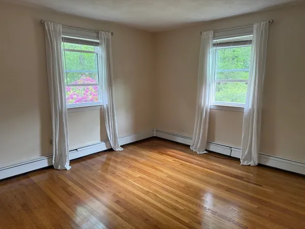 an empty room with wooden floor closet and windows