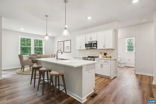 a kitchen with kitchen island granite countertop a sink a counter space appliances and cabinets