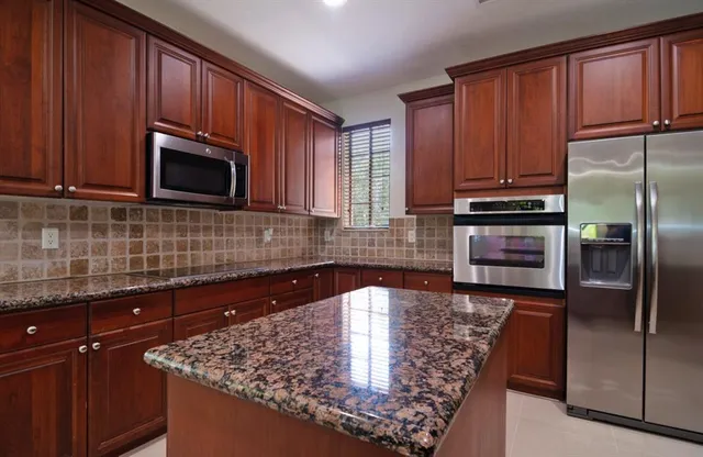a kitchen with granite countertop stainless steel appliances a refrigerator microwave and sink