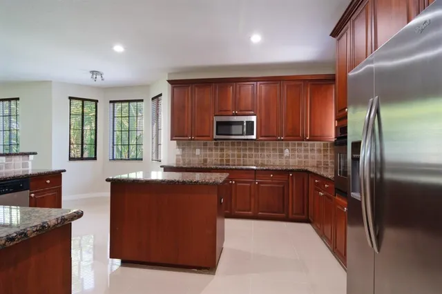 a kitchen with stainless steel appliances granite countertop a refrigerator and a stove top oven