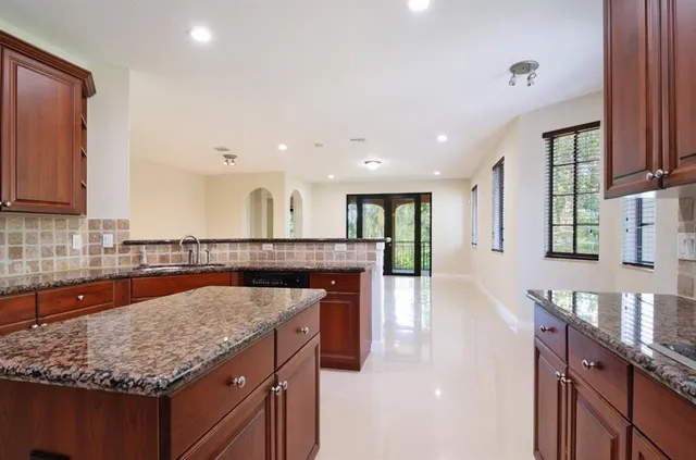 a kitchen with stainless steel appliances granite countertop a counter top a sink a stove and a wooden cabinets