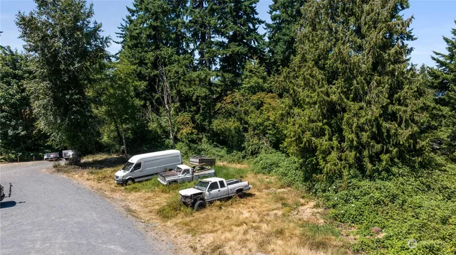 a view of a backyard with lawn chairs under an umbrella