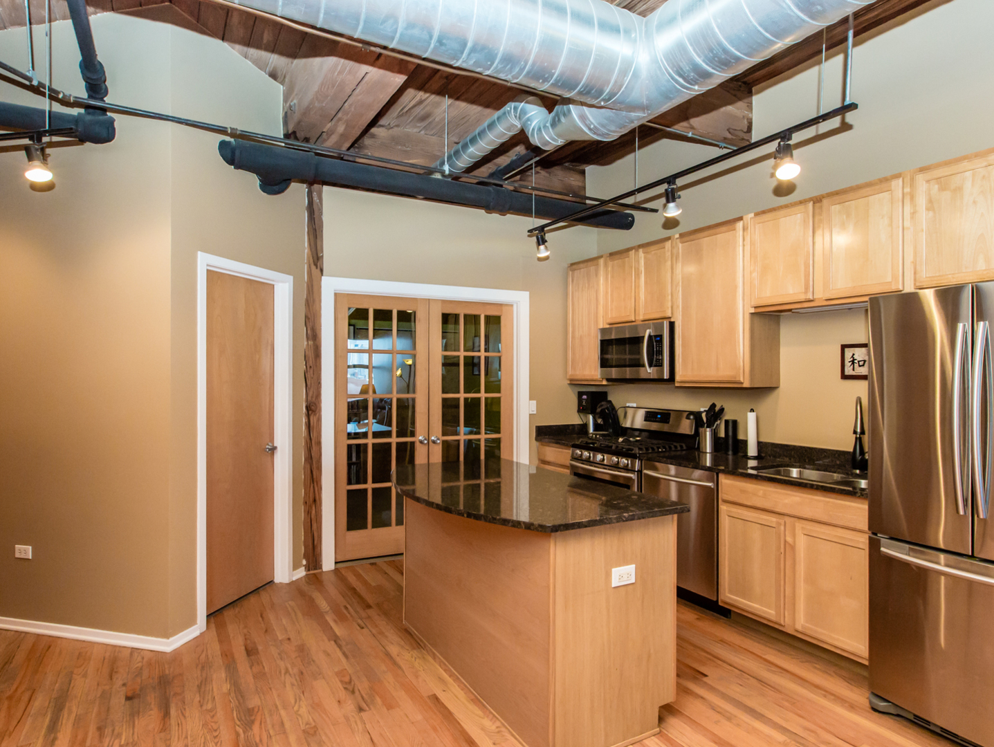 1500 West Monroe Street, Unit 524 Chicago, IL 60607 - Photo 10 of 20 a kitchen with stainless steel appliances granite countertop a refrigerator a sink dishwasher a stove and a microwave oven with wooden floor