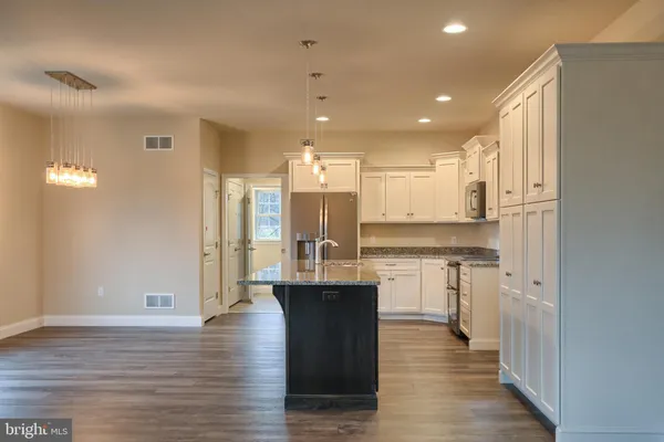 a large kitchen with granite countertop a large counter top appliances and cabinets