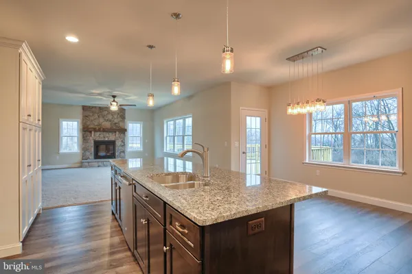 a kitchen with granite countertop center island wooden floor and a ceiling fan