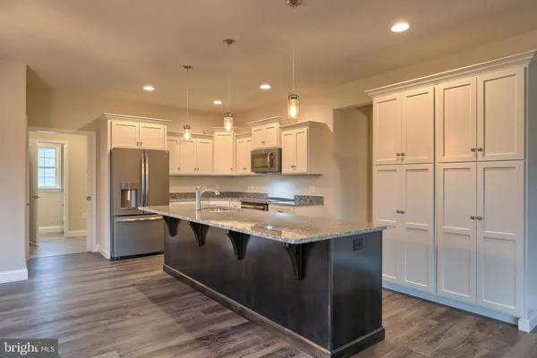 a kitchen with stainless steel appliances granite countertop a refrigerator a sink a stove and white cabinets with wooden floor