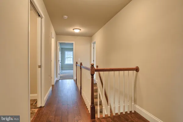 a view of a hallway with wooden floor and staircase