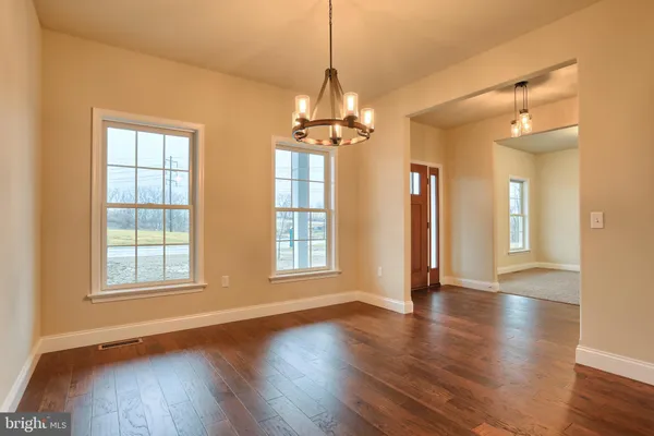a view of a room with wooden floor chandelier and windows