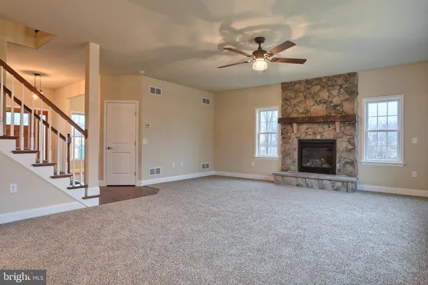 a view of an empty room with chandelier fan and fireplace