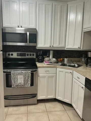 a kitchen with stainless steel appliances granite countertop a stove a sink and a white cabinets