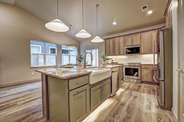 a kitchen with kitchen island granite countertop a stove a sink a oven and a refrigerator