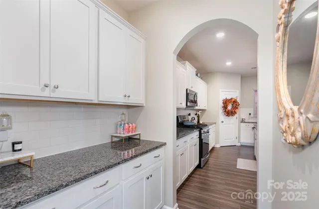 a kitchen with granite countertop a sink dishwasher stove and cabinets