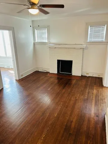 an empty room with wooden floor fireplace and windows