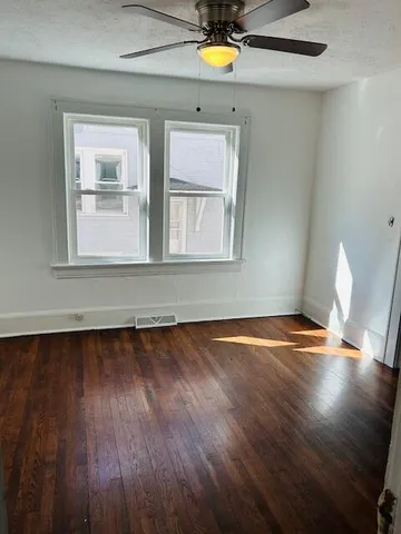 a view of empty room with wooden floor and fan