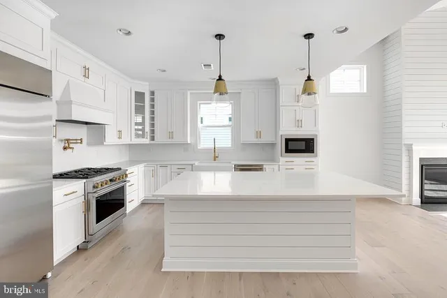 a kitchen with kitchen island a stove a sink a chimney wooden floor and cabinets