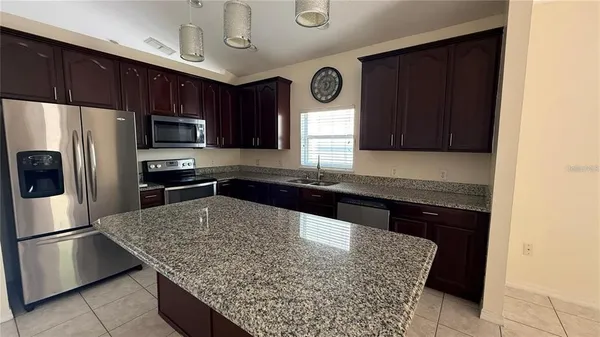 a kitchen with granite countertop a sink a stove and wooden cabinets