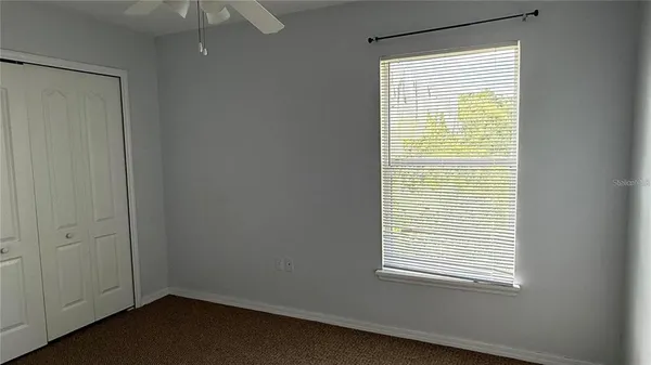 a view of empty room with windows and ceiling fan