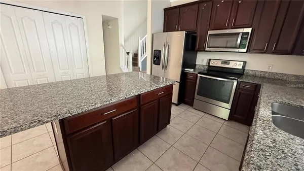 a kitchen with stainless steel appliances granite countertop a sink stove microwave and refrigerator