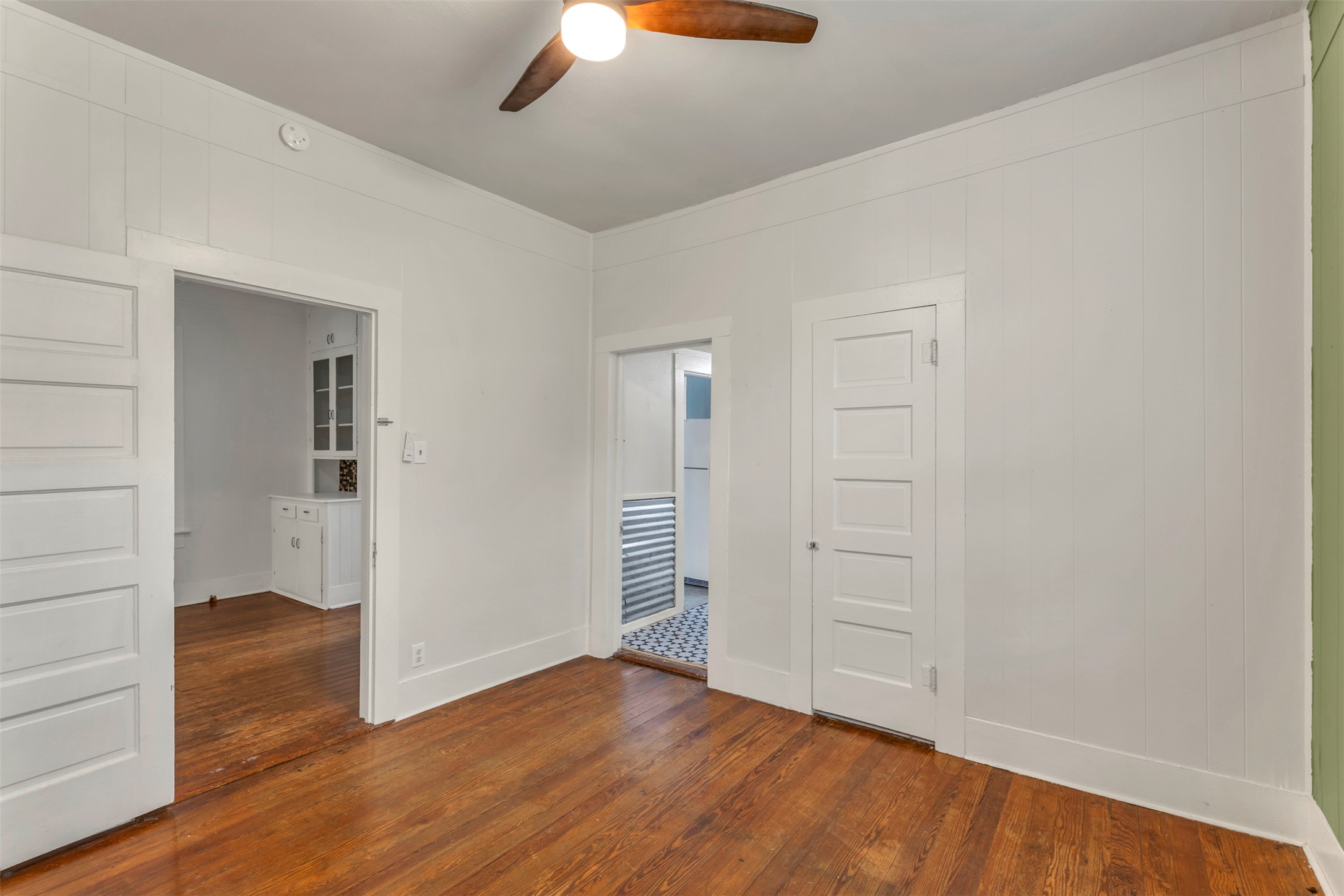 1002 Washburn Street Taylor, TX 76574 - Photo 18 of 29 This room features rich hardwood flooring, white paneled walls, and a ceiling fan