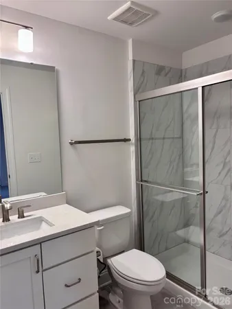 a bathroom with a sink a toilet a mirror and shower