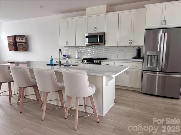 a kitchen with stainless steel appliances granite countertop a table chairs microwave and sink