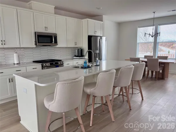 a kitchen with stainless steel appliances a dining table chairs microwave and sink