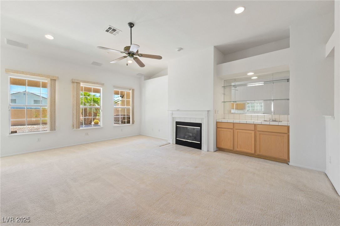 5232 Saranac Road Las Vegas, NV 89130 - Photo 4 of 34 Unfurnished living room featuring light colored carpet, a tiled fireplace, recessed lighting, a sink, and ceiling fan