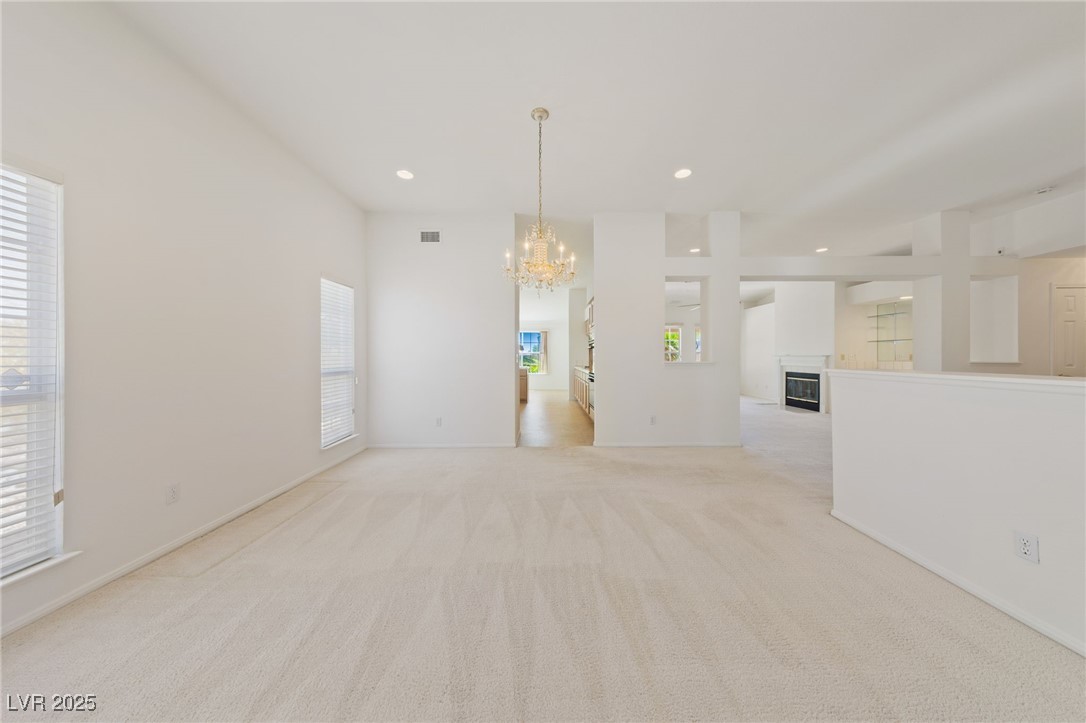 5232 Saranac Road Las Vegas, NV 89130 - Photo 6 of 34 Unfurnished room with a chandelier, light carpet, a glass covered fireplace, recessed lighting, and baseboards
