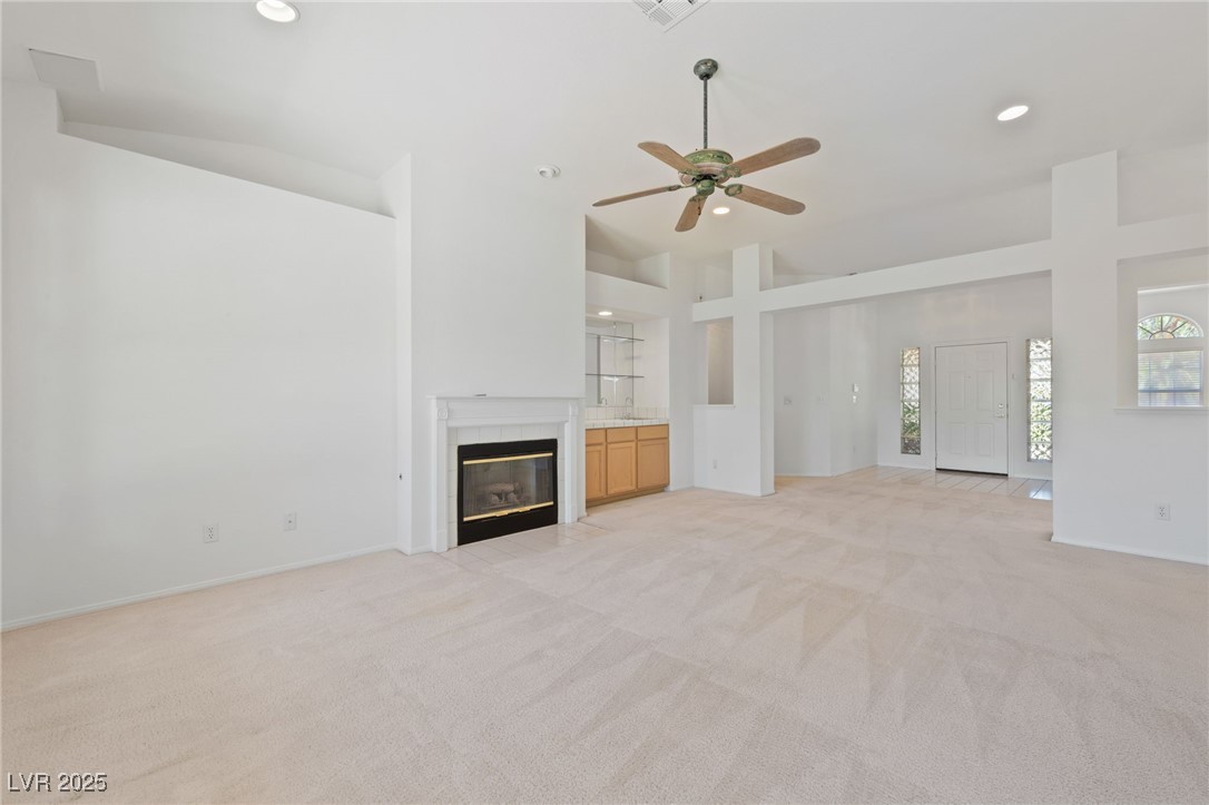 5232 Saranac Road Las Vegas, NV 89130 - Photo 8 of 34 Unfurnished living room with high vaulted ceiling, a premium fireplace, light carpet, ceiling fan, and recessed lighting