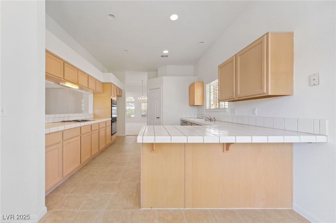 5232 Saranac Road Las Vegas, NV 89130 - Photo 9 of 34 Kitchen featuring a peninsula, light brown cabinets, tile countertops, white gas cooktop, and recessed lighting