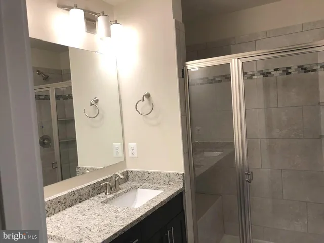 a bathroom with a granite countertop sink mirror and shower