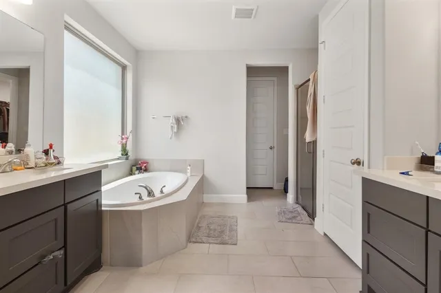 a bathroom with a double vanity sink a mirror and a bathtub